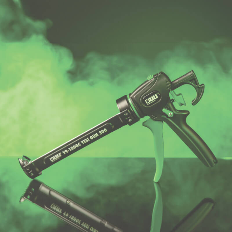 adhesive and sealant gun on green background